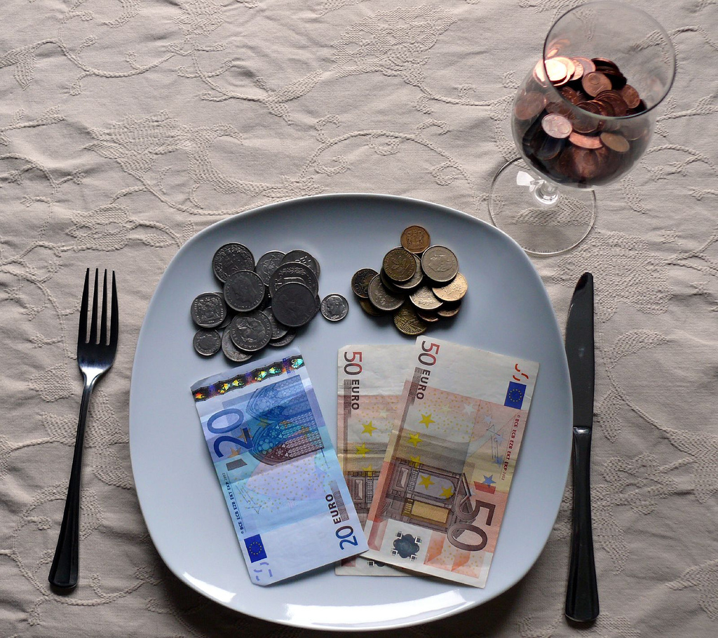 Image of money on a plate and in a wineglass ready to be consumed.